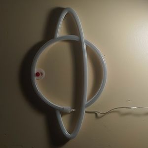 Saturn wall lamp. Neon purple and yellow. Hangs on wall.